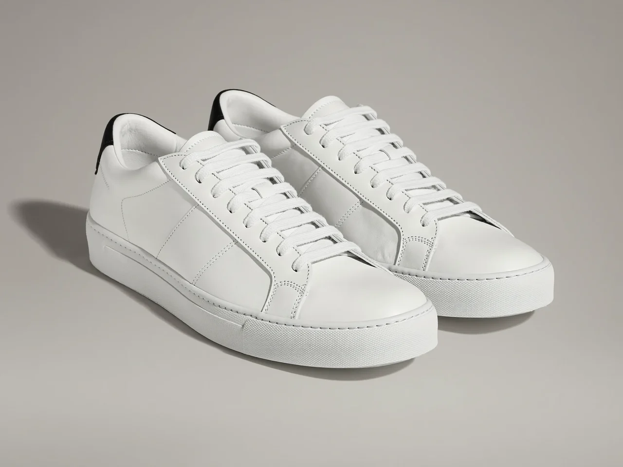Sneakers basse in pelle bianca viste di tre quarti su fondo grigio